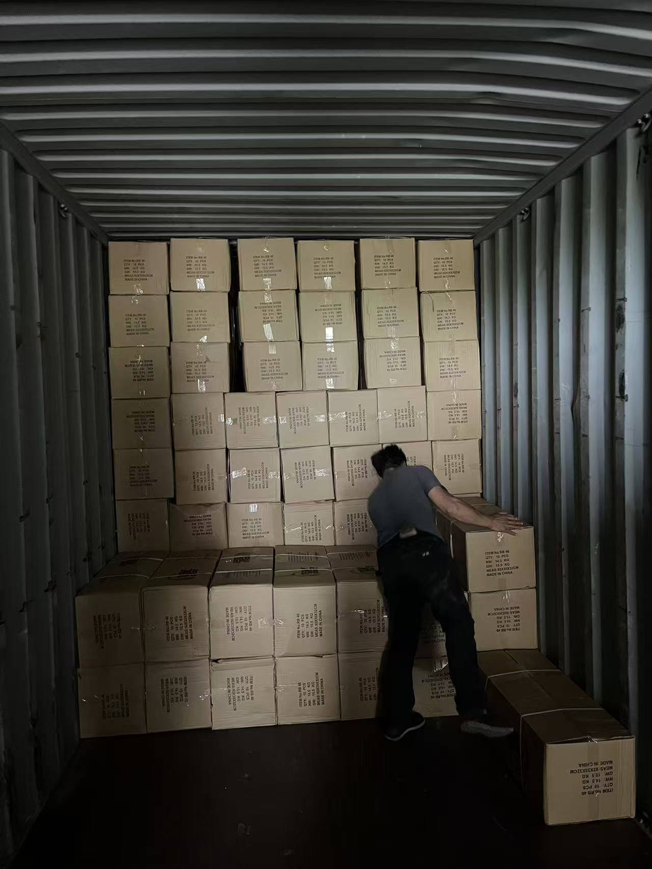 Trabalhador empilhando caixas para exportação dentro de um contêiner