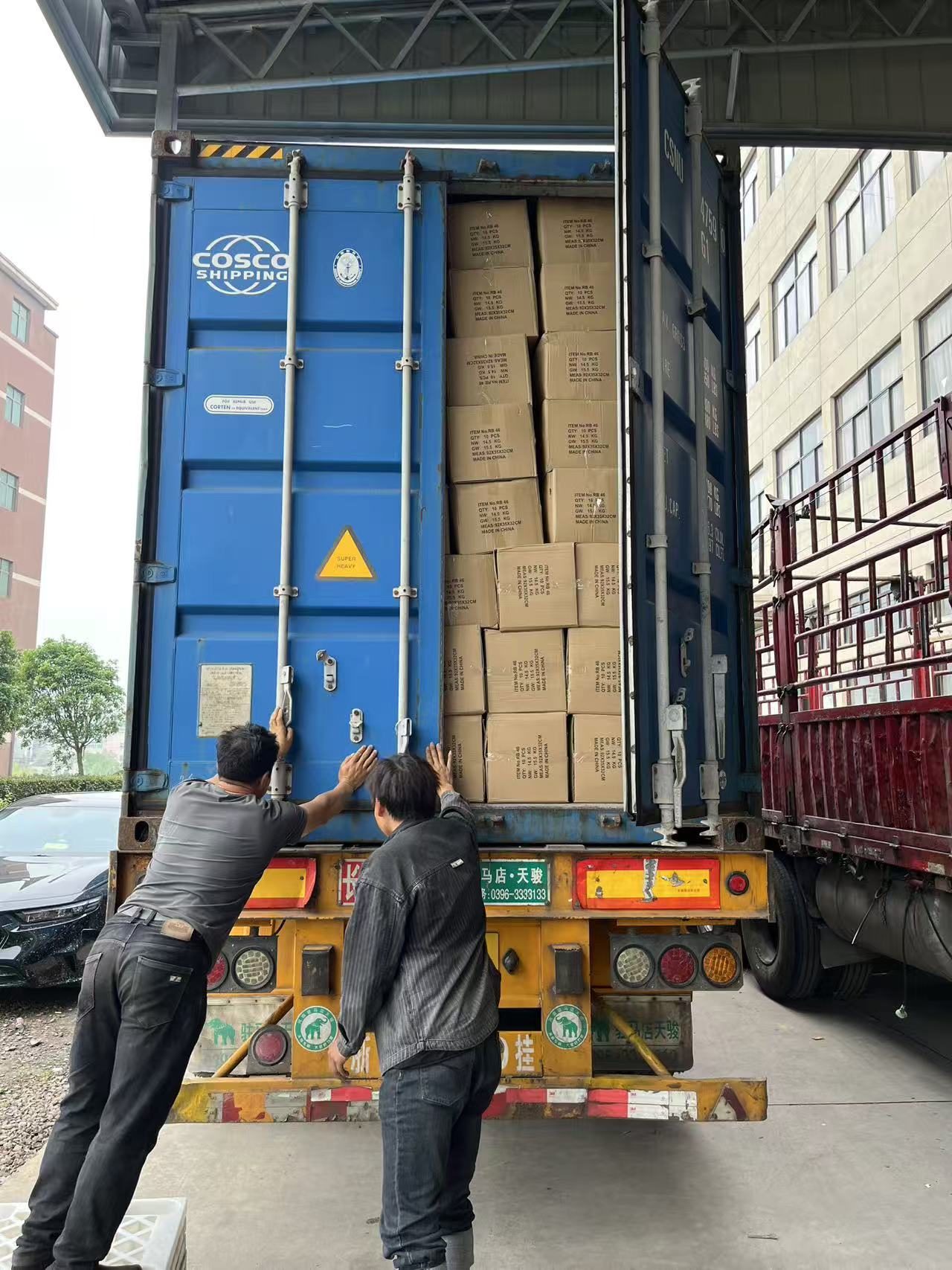 Dois trabalhadores fechando as portas azuis de um contêiner carregado