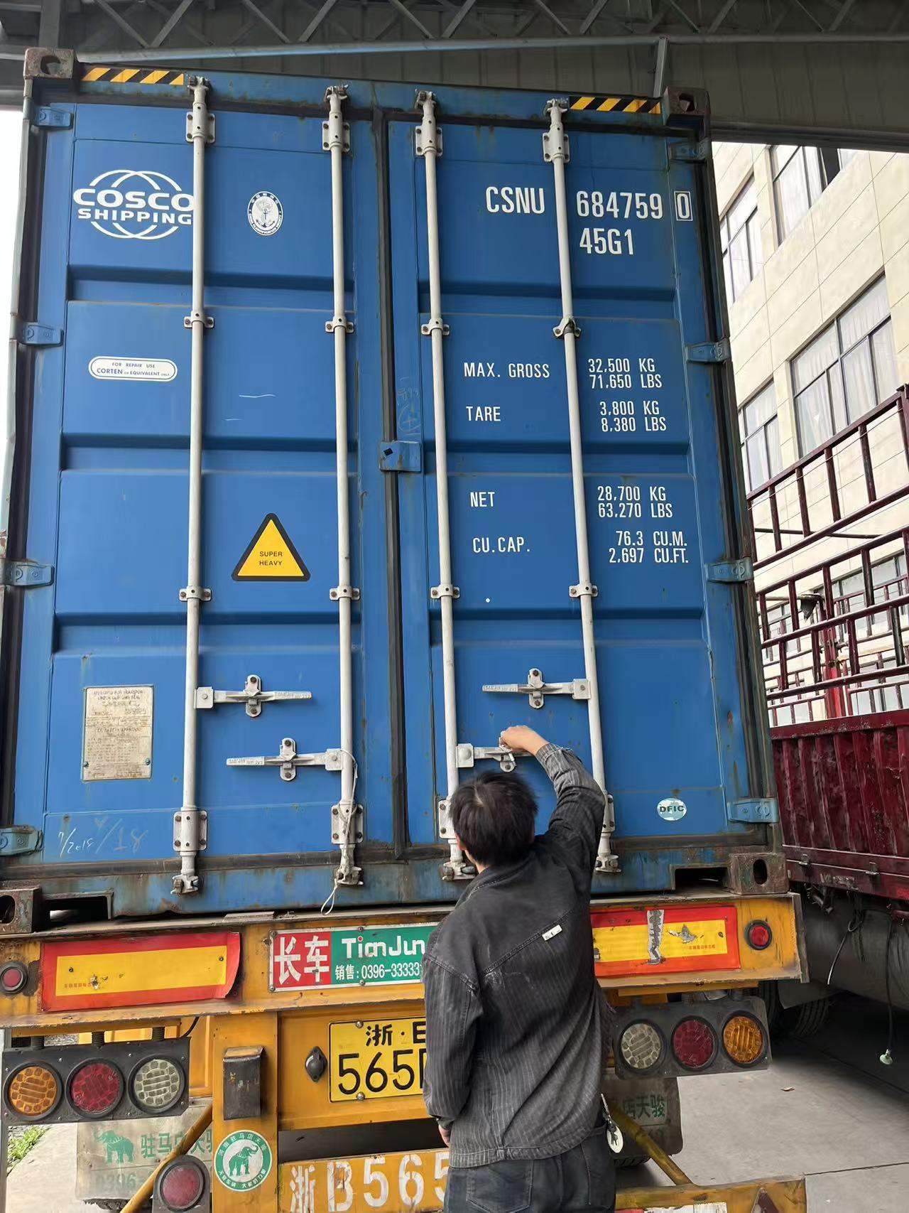 Trabalhador travando a porta de um contêiner azul fechado